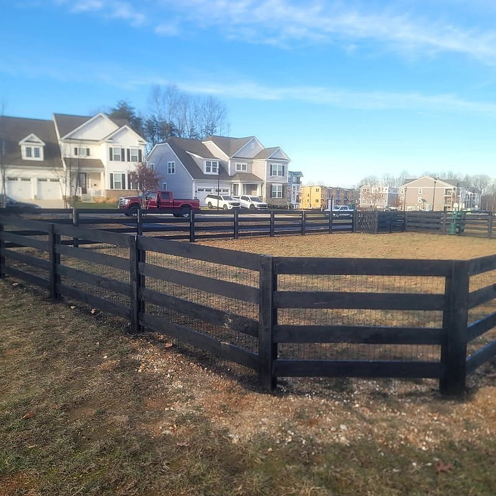Black four board farm fence along a property line
