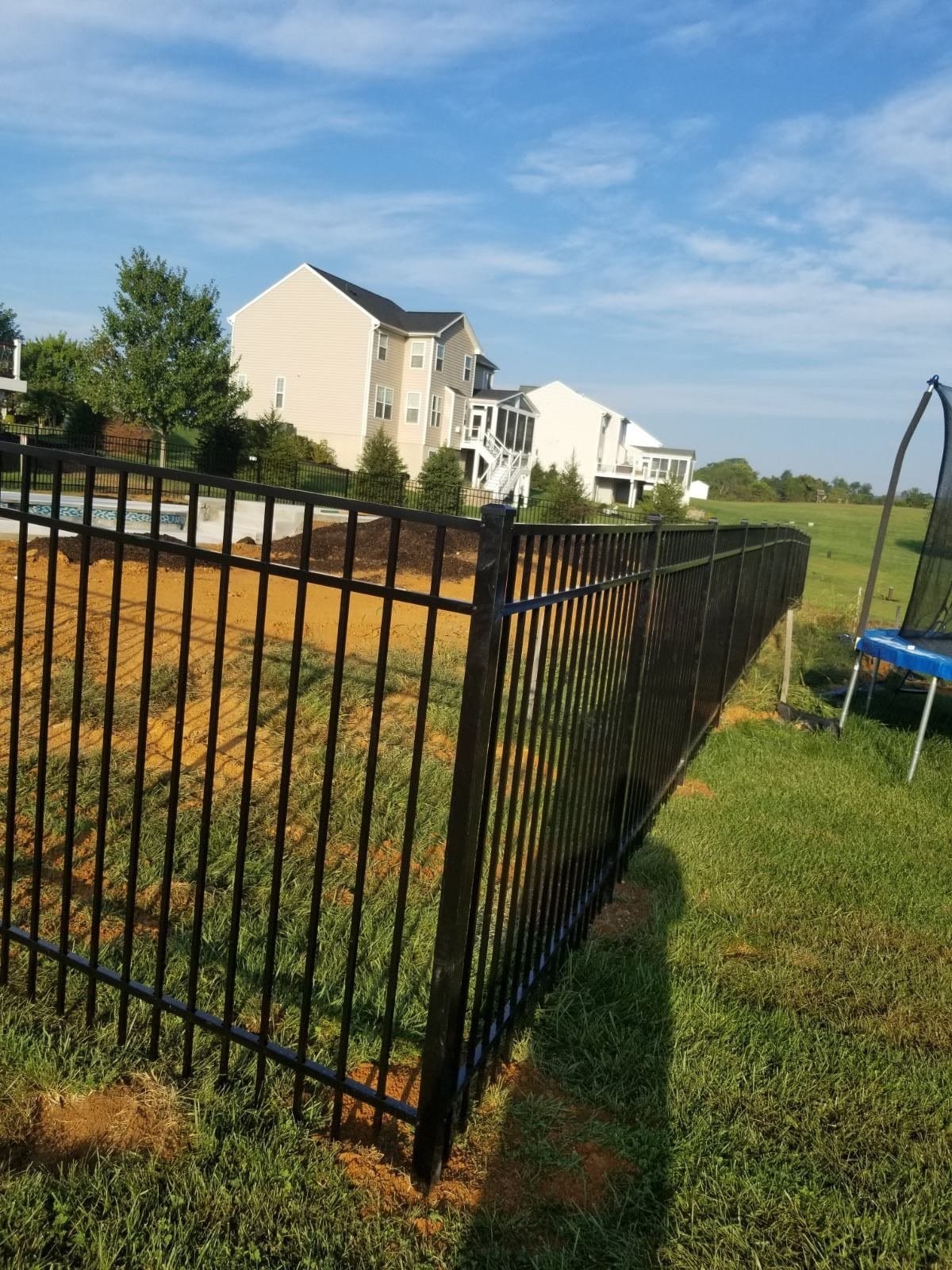 Black aluminum fence turning a back yard corner under an open sky